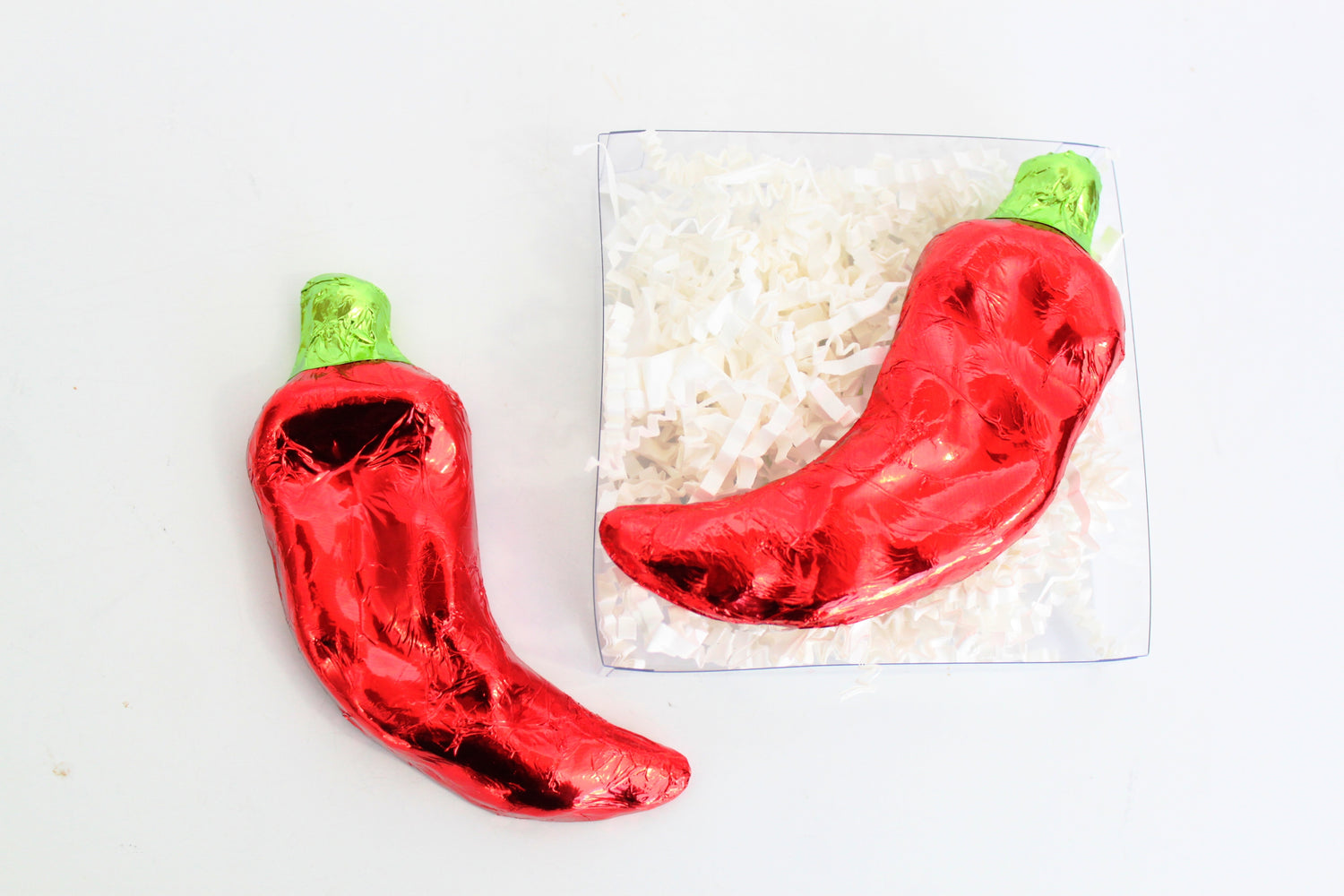 Red chili pepper-shaped chocolates wrapped in foil on a white background
