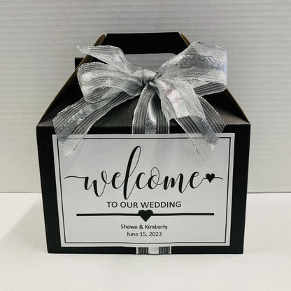 Black gift box with a silver ribbon and personalized wedding welcome label.