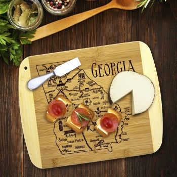 Wooden cutting board with a map of Georgia, cheese, and a knife on a wooden surface.