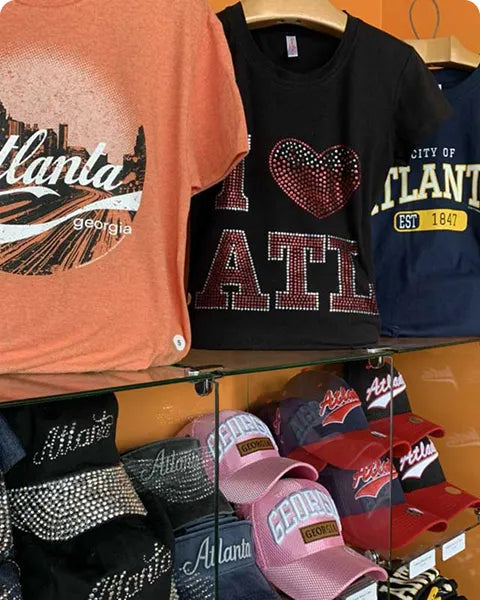 Collection of Atlanta-themed clothing and accessories on a glass display case.