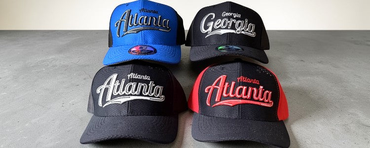 Four baseball caps with 'Atlanta' and 'Georgia' text on a gray surface.