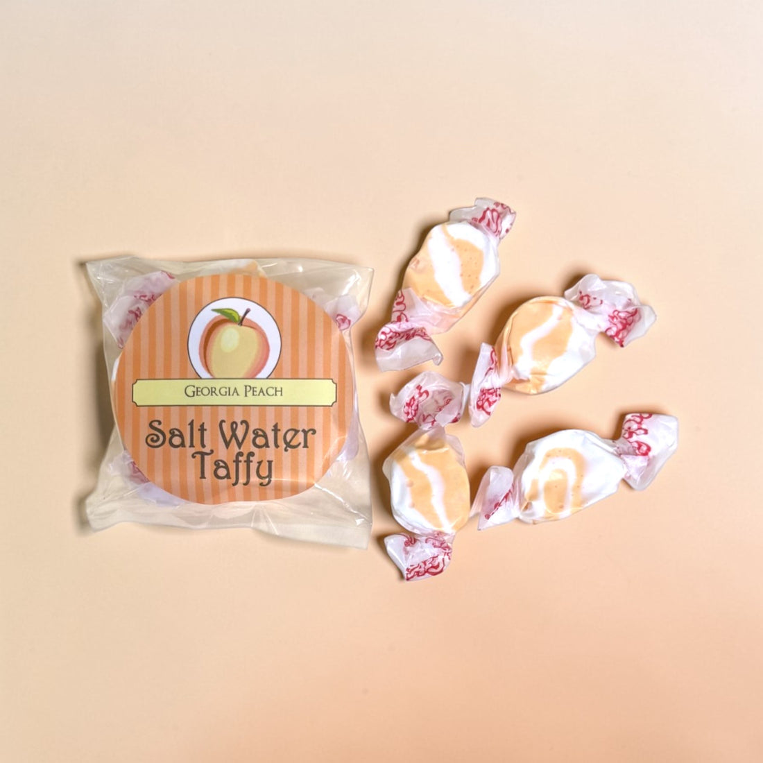 Packaged Georgia Peach Salt Water Taffy with four taffy pieces on a beige background