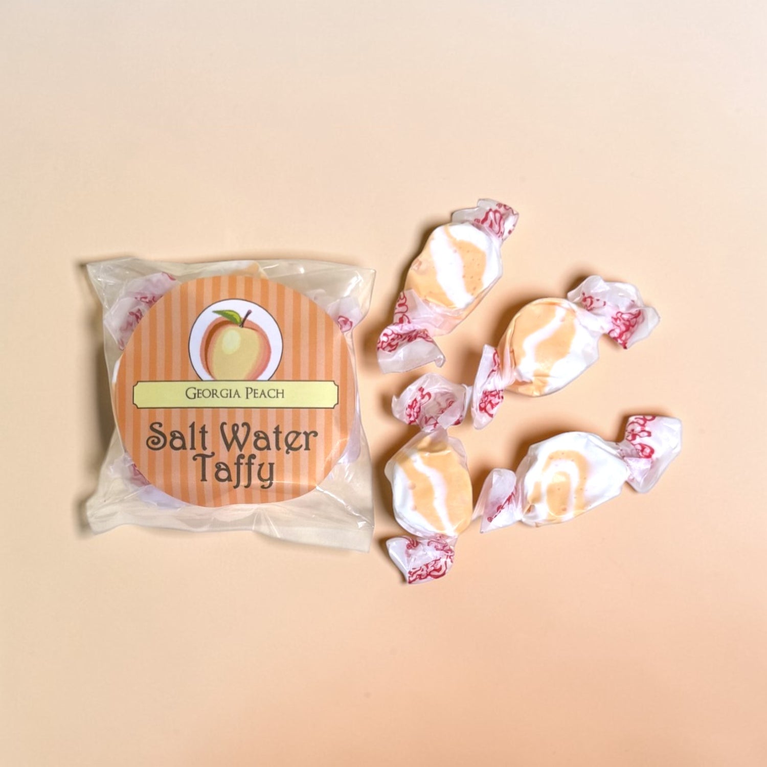 Packaged Georgia Peach Salt Water Taffy with four taffy pieces on a beige background