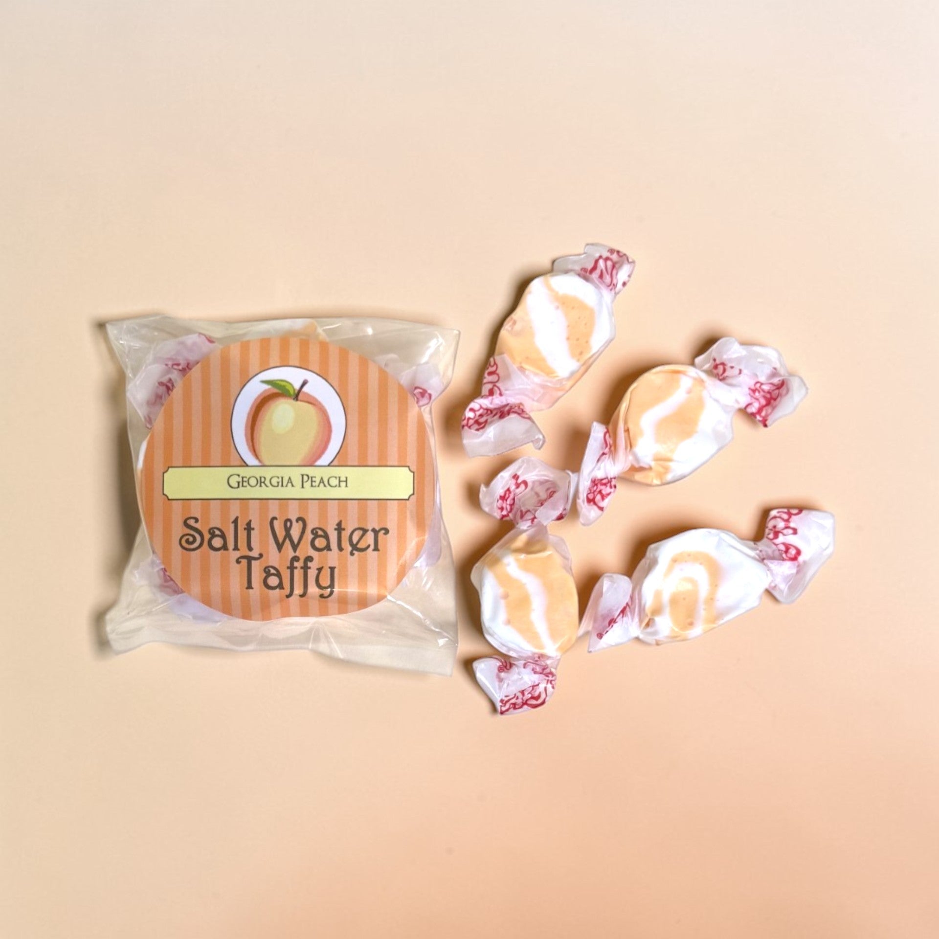 Packaged Georgia Peach Salt Water Taffy with four taffy pieces on a beige background