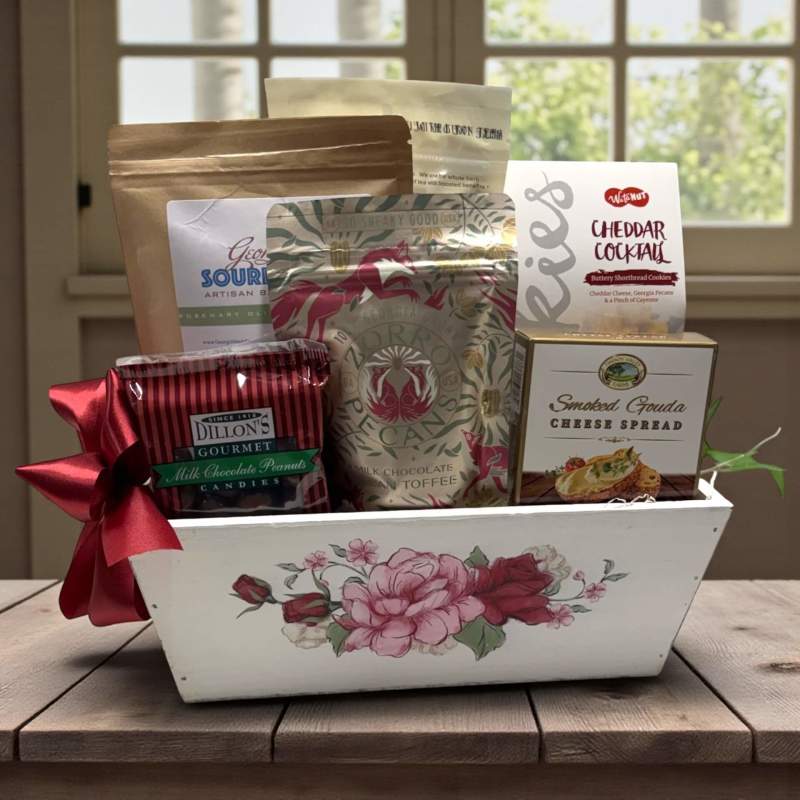 Wood planter with floral motif filled with various Georgia foods including a red bow on a wooden surface.