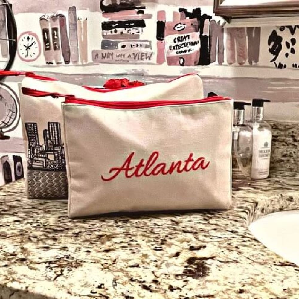 Cream colored set of two travel bags with Atlanta skyline intricately embroidered in black