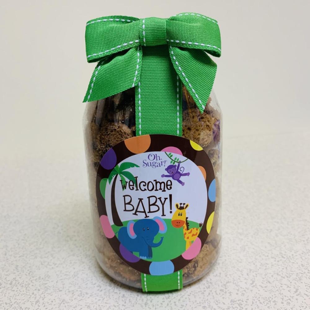 Welcome baby label on plastic jar with coordinating ribbon filled with chocolate chip cookies.