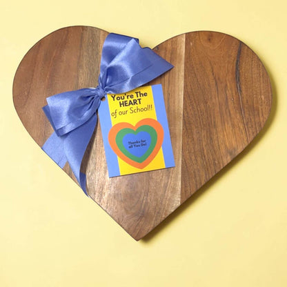 Heart-shaped wooden board with a blue ribbon and a card on a yellow background