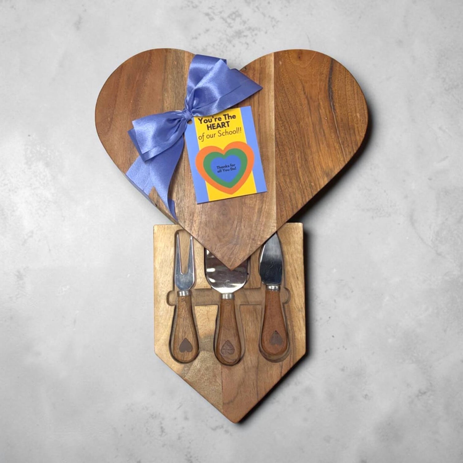 Heart-shaped wooden cutting board set with a gift card on a gray background