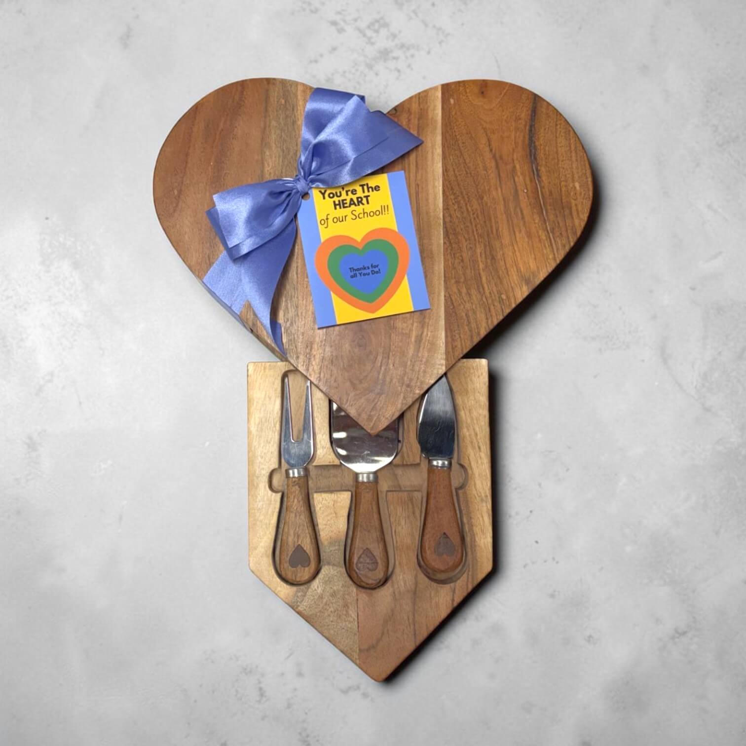 Heart-shaped wooden cutting board set with a gift card on a gray background