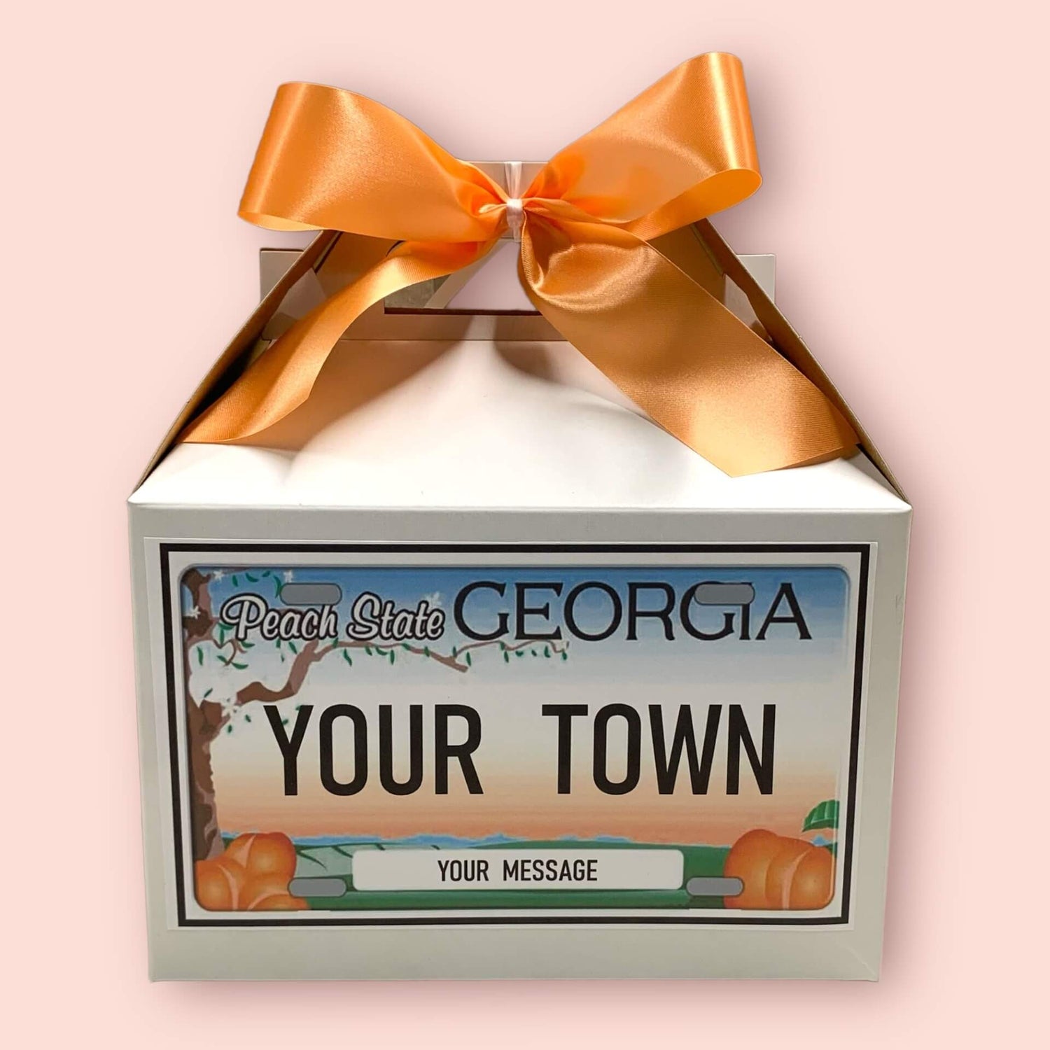 Personalized gift box with a Georgia license plate design and orange ribbon on a pink background