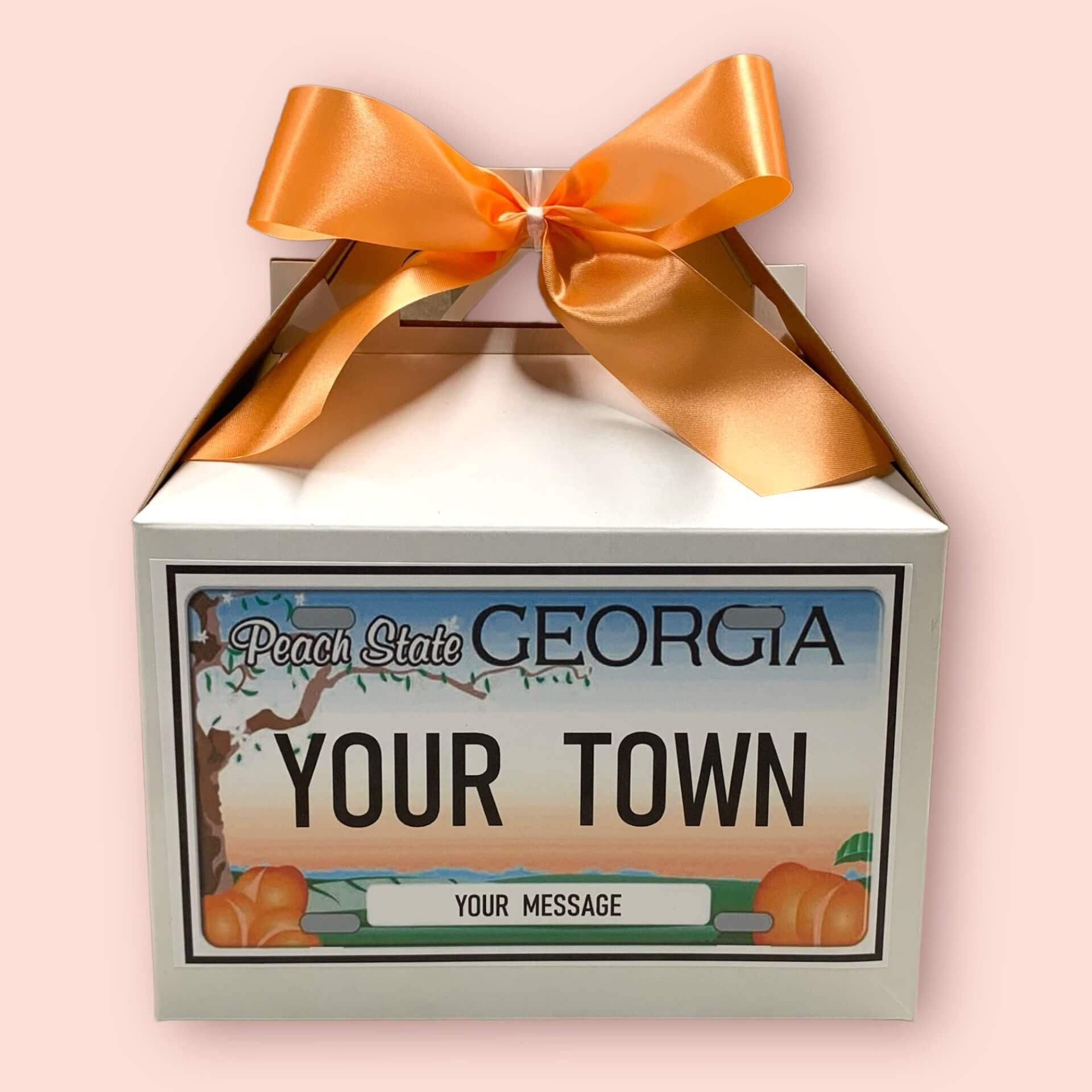 Personalized gift box with a Georgia license plate design and orange ribbon on a pink background