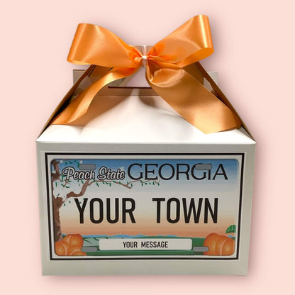 Personalized gift box with a Georgia license plate design and orange ribbon on a pink background